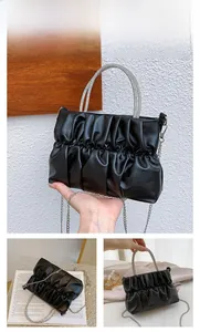 Detail of black pleated handbag with sparkling rhinestone handle and silver chain strap