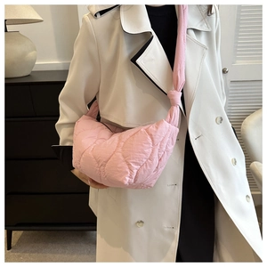 Pink quilted croissant bag styled with a white coat in an elegant urban setting