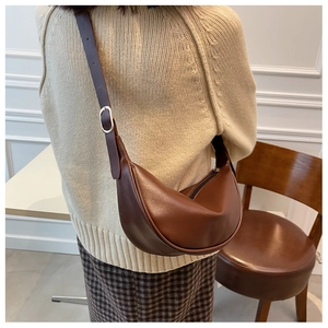 Brown half-moon saddle bag shown on shoulder to display capacity and retro style
