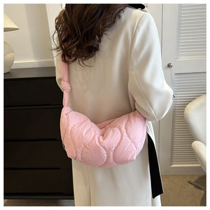 Close-up of light pink quilted crossbody bag with stylish knot strap detail on shoulder
