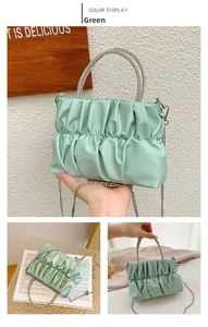 Detail of light green pleated handbag featuring rhinestone metal handle and silver chain strap