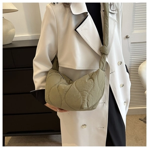 Chic sage green quilted hobo bag with knotted strap shown on model in minimalist interior