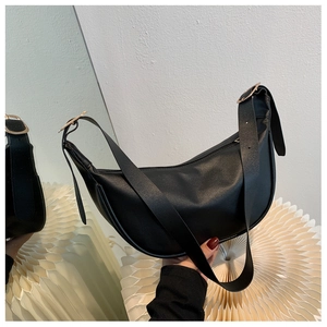 Detail of minimalist black matte leather hobo bag with gold ring and mirror reflection