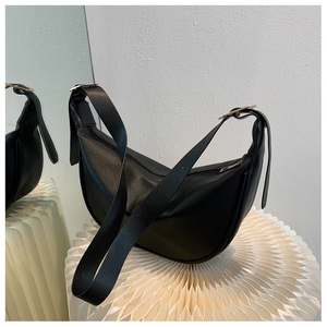 Detail of black faux leather crescent hobo bag featuring adjustable silver buckle strap