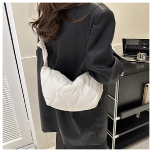 Detailed view of cream quilted puffer bag with wave texture and knotted strap