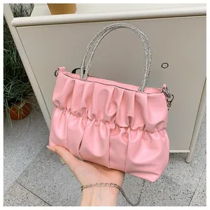 Detailed view of pink pleated handbag featuring a shimmering rhinestone circular handle