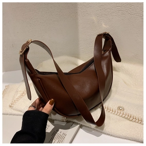 Detail of a brown vintage leather hobo bag with gold buckle on a knitted background