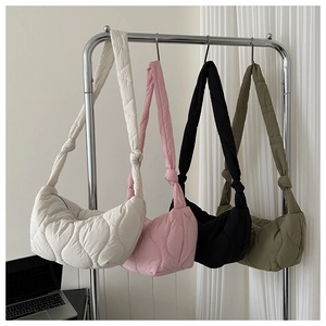 Detailed view of quilted puffer bags in four colors with knot strap and crescent shape