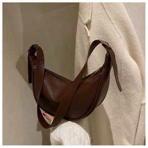 Detail of vintage brown crescent moon bag showing smooth faux leather and gold metal buckle