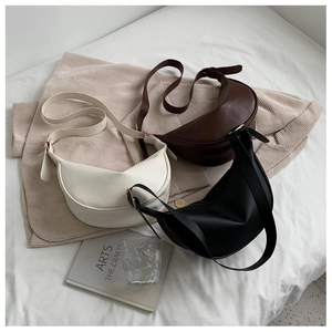 Detailed overhead view of minimalist crescent crossbody bags in beige, brown, and black