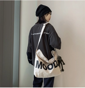 Detail of white canvas tote bag with MOOD lettering and cute monkey plush charm
