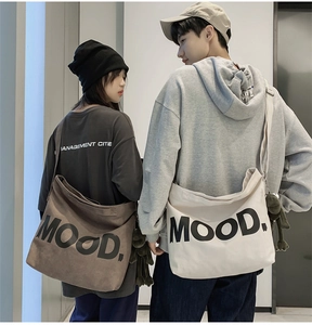 Detail of canvas shoulder bags with MOOD print and cute green frog charms on models