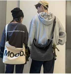 Rear view of models wearing large canvas crossbody bags in beige and grey with Mood print