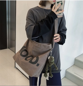 Detail of dark brown canvas tote bag with mood text and green frog plush charm accessory