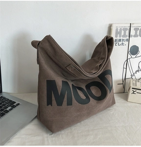 Detail view of large coffee brown canvas bag featuring bold MOOD text and wide shoulder strap