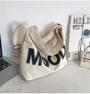 Detail of off-white canvas crossbody bag with MOOD text and adjustable metal buckle
