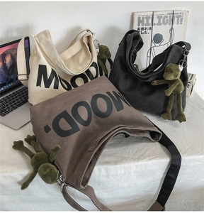 Three canvas tote bags in cream, grey, and coffee colors with a green frog plush charm