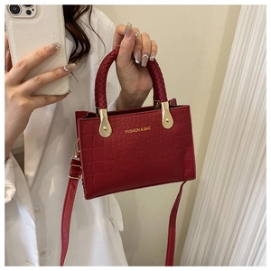 Detail of red crocodile texture PU leather handbag with woven handle and gold hardware