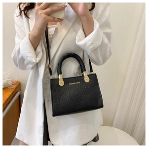 Close-up of black crocodile texture handbag with woven handle and gold fashion lettering