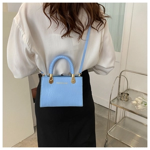Detail view of light blue crocodile pattern tote bag with woven handle and gold accents