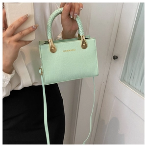 Close-up of mint green crocodile-textured handbag with golden metal hardware and strap