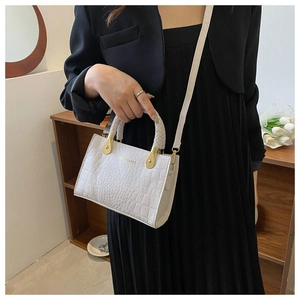 Detail of white crocodile texture tote with woven handle and gold hardware buckles