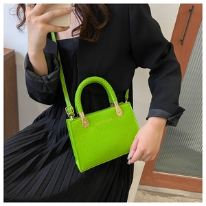 Close-up of neon green crocodile texture handbag with woven handle and gold hardware