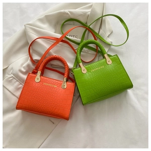 Detail of mini crocodile pattern handbags with woven handles in orange and neon green colors