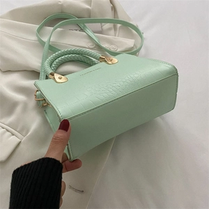 Detail of light green crocodile pattern bag with woven handle and gold hardware
