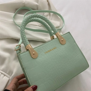 Detail of mint green crocodile-textured handbag with a distinctive woven rope handle