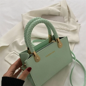 Detail of mint green faux crocodile leather handbag with woven handle and gold hardware