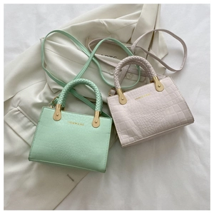 Detail of crocodile embossed crossbody bags with woven handles and golden hardware