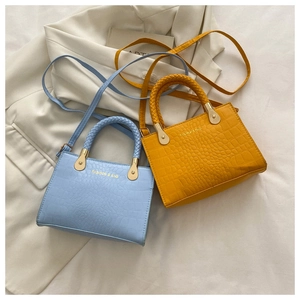 Detail of crocodile pattern mini crossbody bags with woven handles in blue and yellow