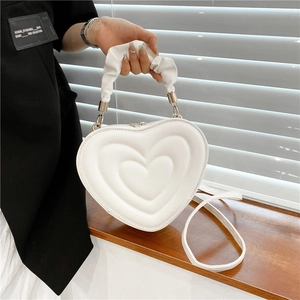 White heart-shaped quilted leather crossbody bag with ruffled handle and shoulder strap