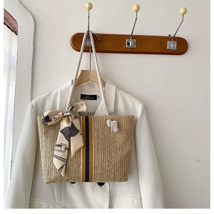 Straw tote bag detail with blue-yellow stripes, rope handles and decorative silk scarf