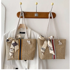 Straw tote bag detail with colorful woven straps and patterned silk scarf accents