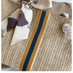 Close-up of handwoven straw tote with blue-yellow stripes and silk scarf detail