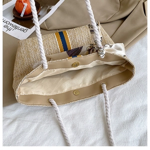 Detail view of woven straw tote bag with striped pattern, silk scarf, and magnetic closure