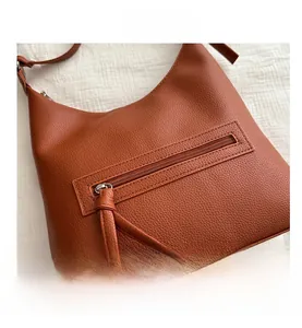 Détail de la poche zippée arrière sur le sac cabas orange en cuir à texture grainée