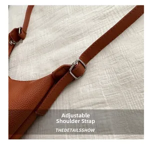 Détail de la bandoulière en cuir marron avec boucle argentée et texture litchi