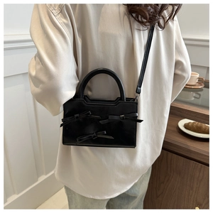 Détail d'un sac à main noir chic avec trois nœuds décoratifs sur une table de café