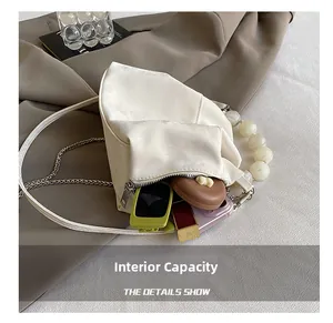 Detail showing the internal capacity of the white cloud bag with pearls and essentials