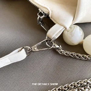 Macro detail of cream cloud bag featuring silver metal hooks and marble pattern beads