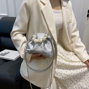 Detail of silver metallic cloud bag with large pearl handle and metal chain strap