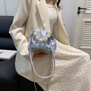 Detail of light blue cloud bag featuring large pearl handle and silver metal chain