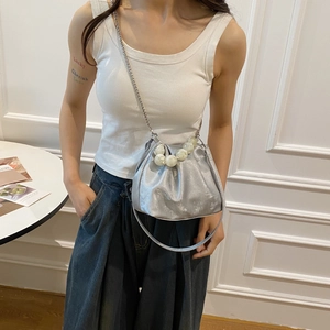 Detailed view of silver pleated clutch featuring faux pearl handle and metal chain strap