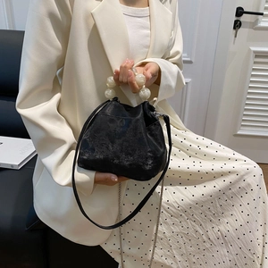 Detail of black matte cloud bag featuring a large pearl handle and stylish chain strap
