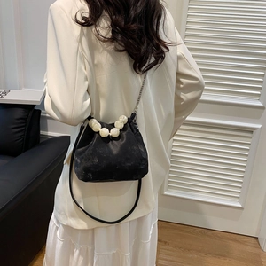 Detail of black matte cloud bag with large white pearl handle and silver chain strap