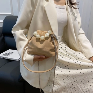 Detail of beige cloud bag featuring large pearl handle and metal chain shoulder strap