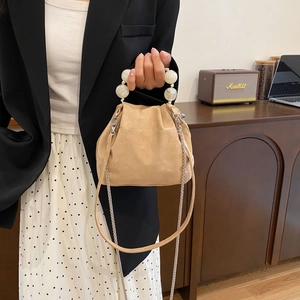 Detail of macaron pearl handle on beige cloud bag with elegant gold chain strap